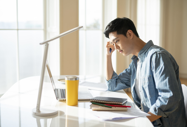 自宅でPCを見ている男性